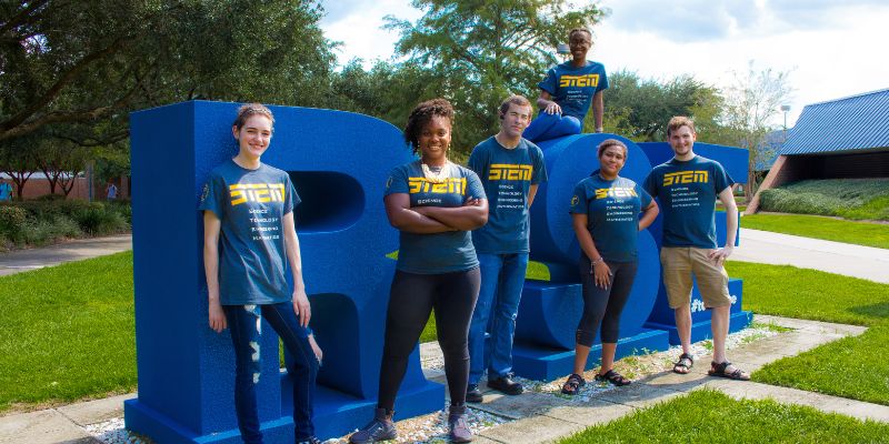 STEM students posing for photo on sign