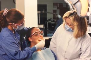 Archival picture of TSC dental students cleaning a client's teeth.