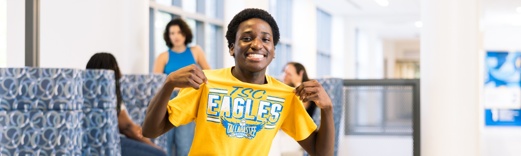 Student smiling and showing off TSC Eagles shirt.