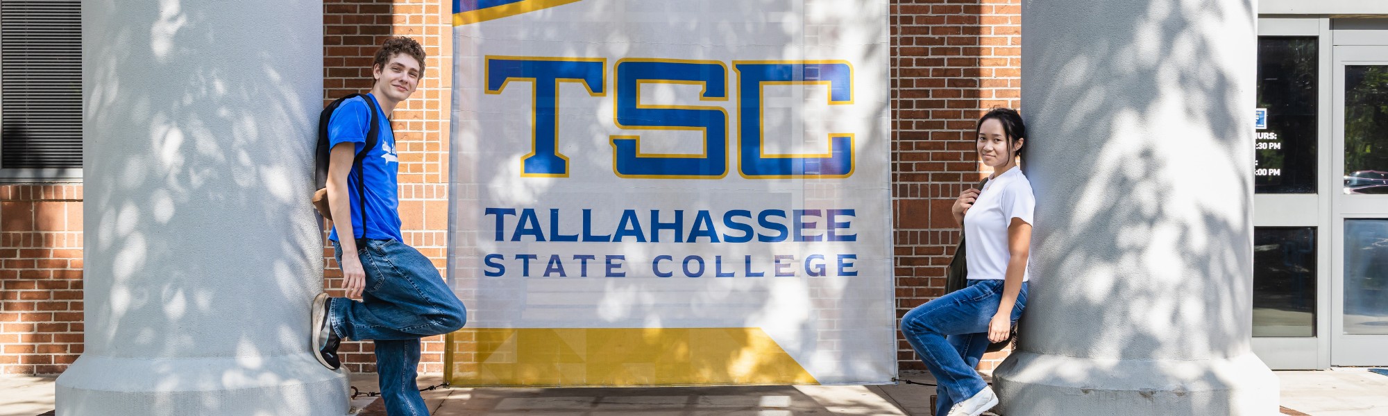 Two students standing on opposite signs of a TSC banner.